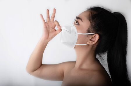 Close up of a woman putting on a respirator N95 mask to protect from airborne respiratory diseases...