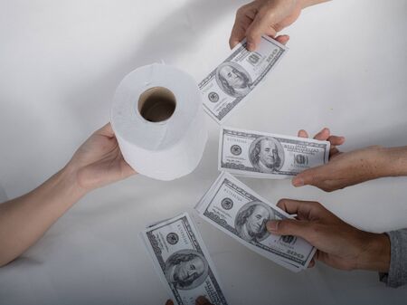 Close up sell buy tissue, hand holds toilet paper tissue and money of 100 US dollars banknote a lot of, That was It costs expensive price and high priced products concept, Doomsday of people panicの写真素材