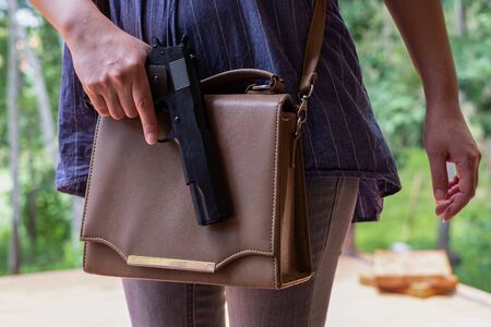 Young Asia woman putting a gun in her handbag, Women hand pulling a pistol out of the bag on the...