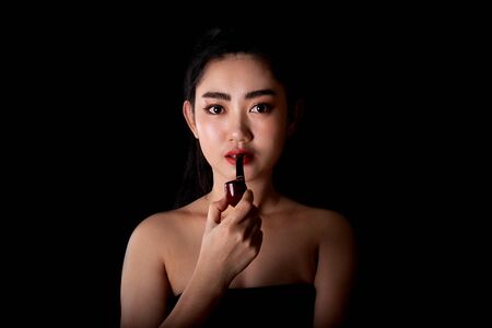 Portrait beautiful Asia young women with a smoking pipe tobacco on the black background, Studio shot close up Image of cigarette smoke spread in lady's handの写真素材