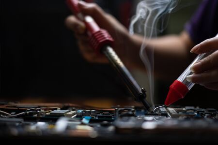 Close-up hand technician repairing broken laptop notebook computer with electric soldering Ironの写真素材