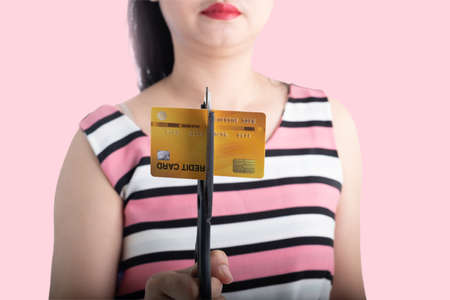 Portrait of young Asian woman cutting up a credit card with scissors to stop spending on shopping at...