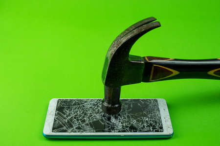 Hammering the phone smartphone screen is cracked on green backgroundの写真素材