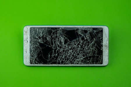Smartphone screen is cracked on green backgroundの写真素材