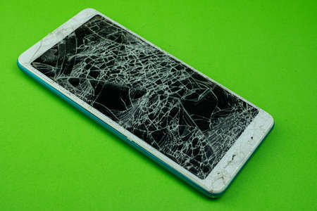 Smartphone screen is cracked on green backgroundの写真素材