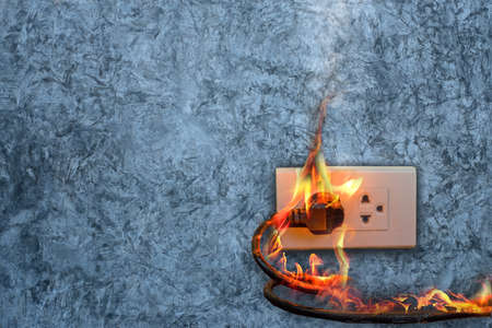On fire electric wire plug Receptacle on the concrete wall exposed concrete background with copy spaceの写真素材