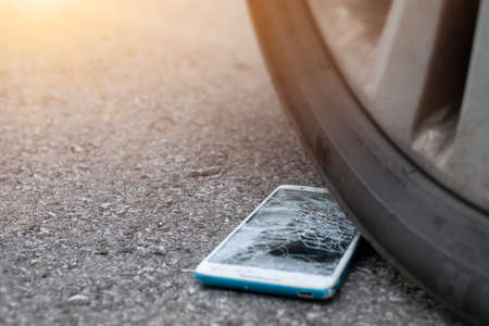 Smartphone screen is cracked flat on the road from moving a car tire at the front and back...
