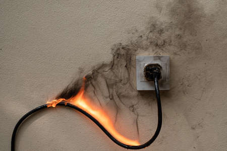 On fire electric wire plug Receptacle on the concrete wall exposed concrete background with copy spaceの写真素材