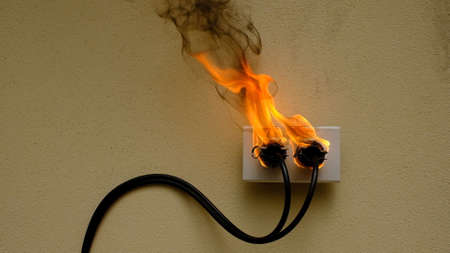 On fire electric wire plug Receptacle on the concrete wall backgroundの写真素材