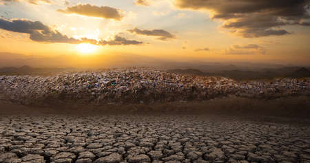 mountain large garbage pile and pollution at the sun is setting on cracked soil in arid areas of...