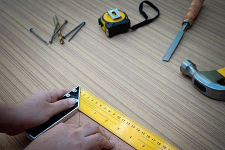 Female hands using a try square to check that the woodworking corners are square with a set...
