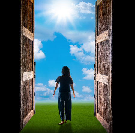Woman walking into the light has cloud and sun through the open big doorの写真素材