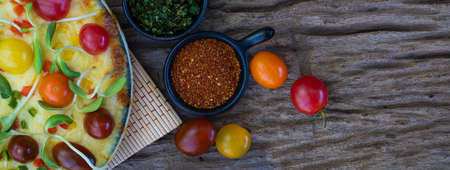 Close up homemade vegetable pizza with cherry tomatoes and other ingredients on a wooden backgroundの写真素材