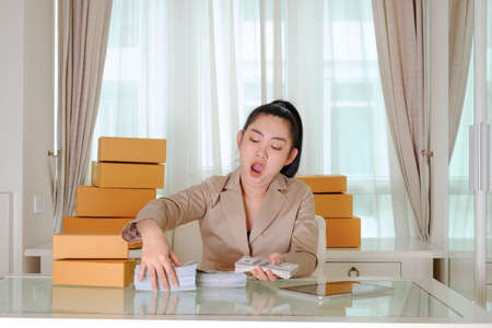 Business woman yawning counting money in office roomの写真素材