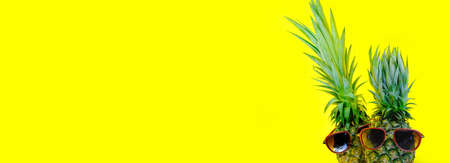 Pineapple wearing red sunglasses on isolated yellow background, minimal concept