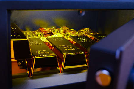 Steel safes box full of coins stack and gold bar on the wooden tableの写真素材