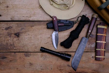 A knife with equipment for survival in the forest  on an old wooden floor