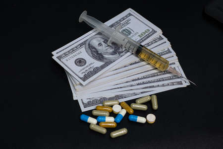 Drug medicine syringe and money banknote on the black backgroundの写真素材