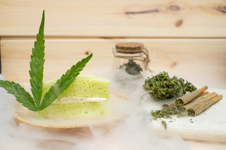 Pre-Roll cannabis joints and cake with cannabis buds in a clear glass jar laying on the sackclothの写真素材