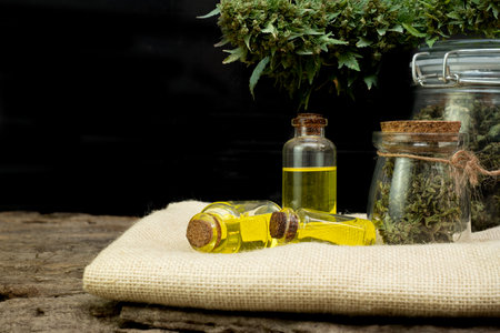 Oil cannabidiol CBD with bud marijuana in a clear glass jar on wooden and the black backgroundの写真素材