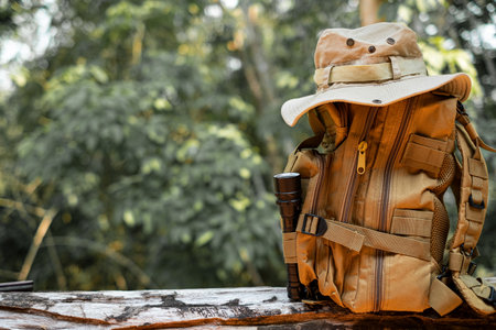 Bucket Hat and backpack hiking with a flashlight resting on wooden timber in the background is a forestの写真素材