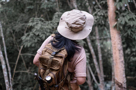 Back view of a young woman with backpack hiking in the deep jungleの写真素材