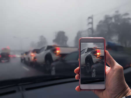 Close Up Of A Hand Taking Photo Of Car Accident Through Smartphone, Car crash from car accident on the road in a city car pickup wait insurance smartphone call a car insurance.の写真素材