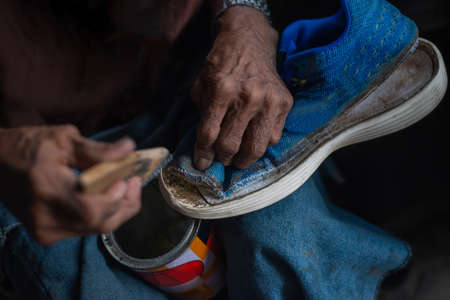Shoemakers at work in their workshop.Man fixing sneakers with a glue.