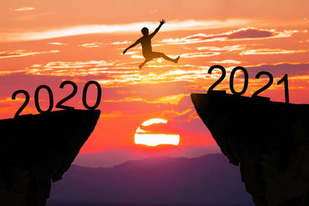 Silhouette man jump between 2020 and 2021 years with sunset background, Success new year concept.の写真素材