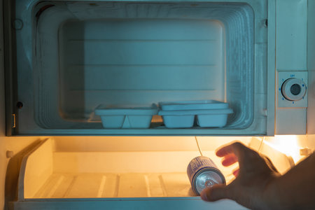 Man hand picking soft drink can from old refrigerator.の写真素材