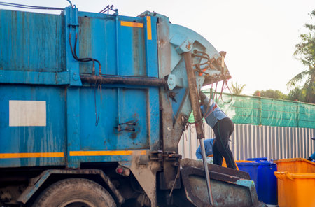 Garbage collector on the garbage truck.Sweeper or Worker are loading waste into the garbage truck carrier.の写真素材
