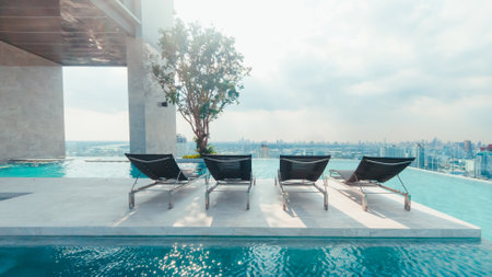 Relaxing chair on rooftop swimming pool with beautiful morning cityscape view.