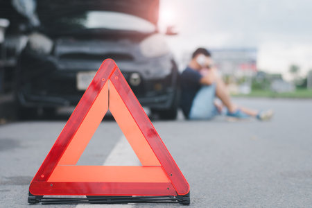 Red warning triangle with a broken down car,Emergency triangle on the road, stopped car and man...