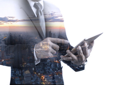 Double exposure of businessman using the tablet with cityscapeの写真素材