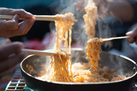 Group of friend enjoy noodles in restaurant at night,Partial view of people eating noodles with chopsticks.の写真素材