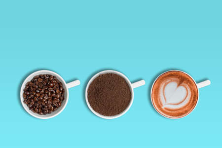 Coffee beans, ground coffee and cup of latte coffee over blue background with copy space for text.の写真素材