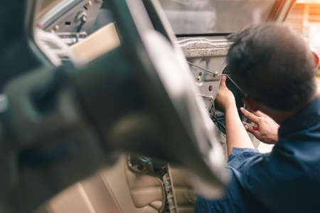 Mechanic installing car central door lock motor,the car's door has changed after the accident and the installation continues.の写真素材