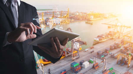 Douple exposures of Businessman touching tablet for analyze stock at logistics port and world map with logistic network distribution on background, transportation trading business concept,の写真素材