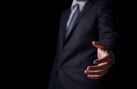 Young man giving empty hand on black or isolated background, Businessman holding open hand, giving showing concept, copy space for text.の写真素材