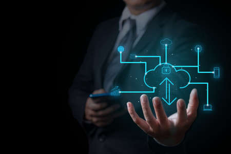 businessman holding on cloud button on virtual screen over dark background, Business innovation technology concept.の写真素材