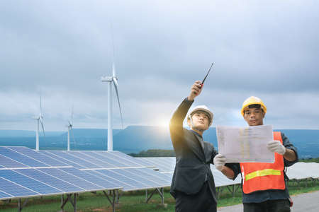 Green energy engineer and workers are conducting on-site inspection visits at the new energy base, The engineer is checking the solar cell power system.の写真素材