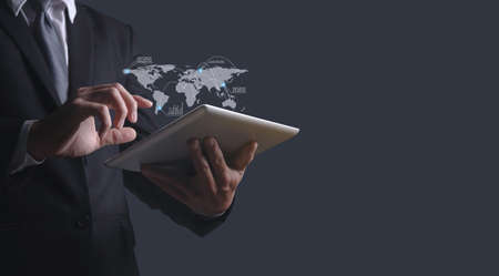 Businessman hand holding tablet global marketing on gray background, Midsection of businessman holding digital tablet.の写真素材