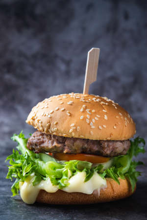 A delicious homemade cheeseburger with French mustard sits on the chopping board. On the background.の写真素材