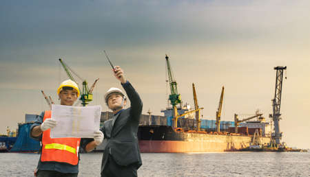 Executives businessmen and engineers or foreman. Quality Control Officer inspecting warehouses at containers yard for international shipping businesses,copy space for text.の写真素材