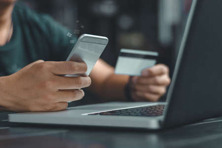 Online payment,Man's hands holding a credit card and using smart phone for online shopping,Credit card online technology shopping concept.の写真素材