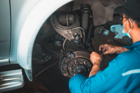 Young man using tool for repair brake car a part of wheel tire in garage.の写真素材