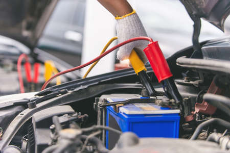 Close up of hand Charging car battery with electricity trough jumper cables, copy space for text.の写真素材