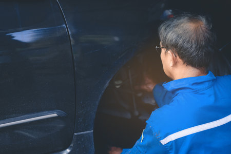 Male mechanic repairing suspension system of car in garageの写真素材