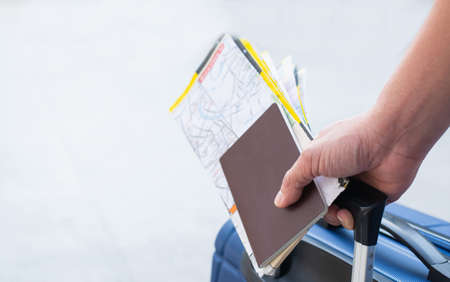 Traveler man holding passports, map for travel with luggage for the trip, copy space for text.の写真素材