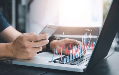 Business investor using mobile with laptop  to analysis beautiful virtual stock market chart ,...